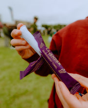 Load image into Gallery viewer, Person holding a lavender refreshment towel with a blurred outdoor background
