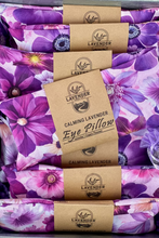 Load image into Gallery viewer, A stack of lavender eye pillows with a purple and pink floral pattern, each wrapped in a kraft paper band labeled 'LAVENDER CALMING LAVENDER Eye Pillow'.
